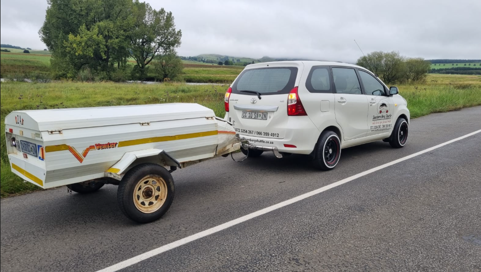 Southern Berg Shuttle Avanza towing its luggage trailer past green Underberg farmland