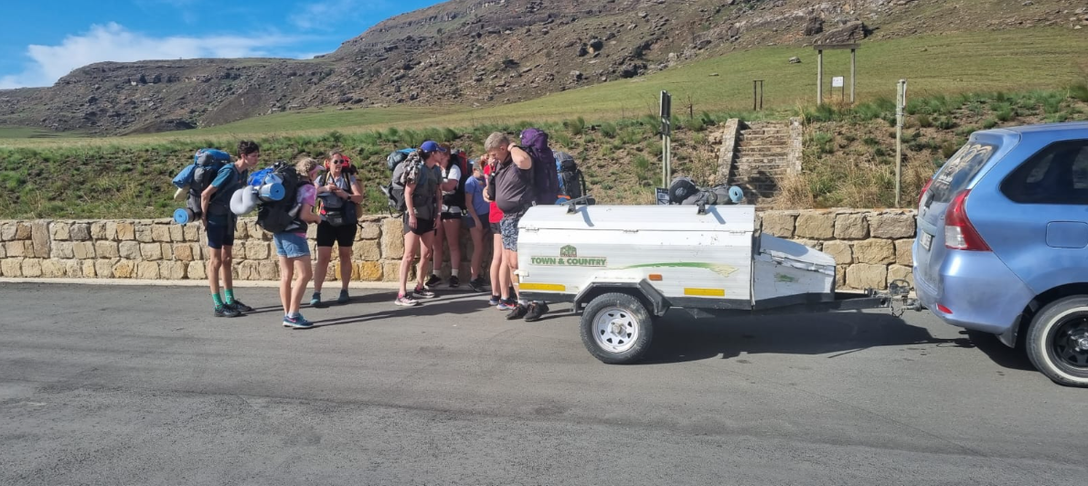 Hiking group loading packs into the shuttle trailer at a Drakensberg trailhead
