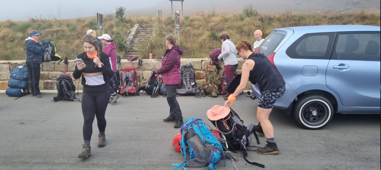 Hikers unloading packs at a misty Drakensberg trailhead beside the shuttle